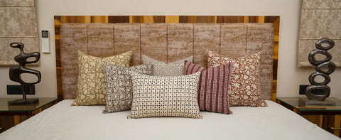 Bed with a wooden headboard adorned with unique throw pillows in a stylish living space.